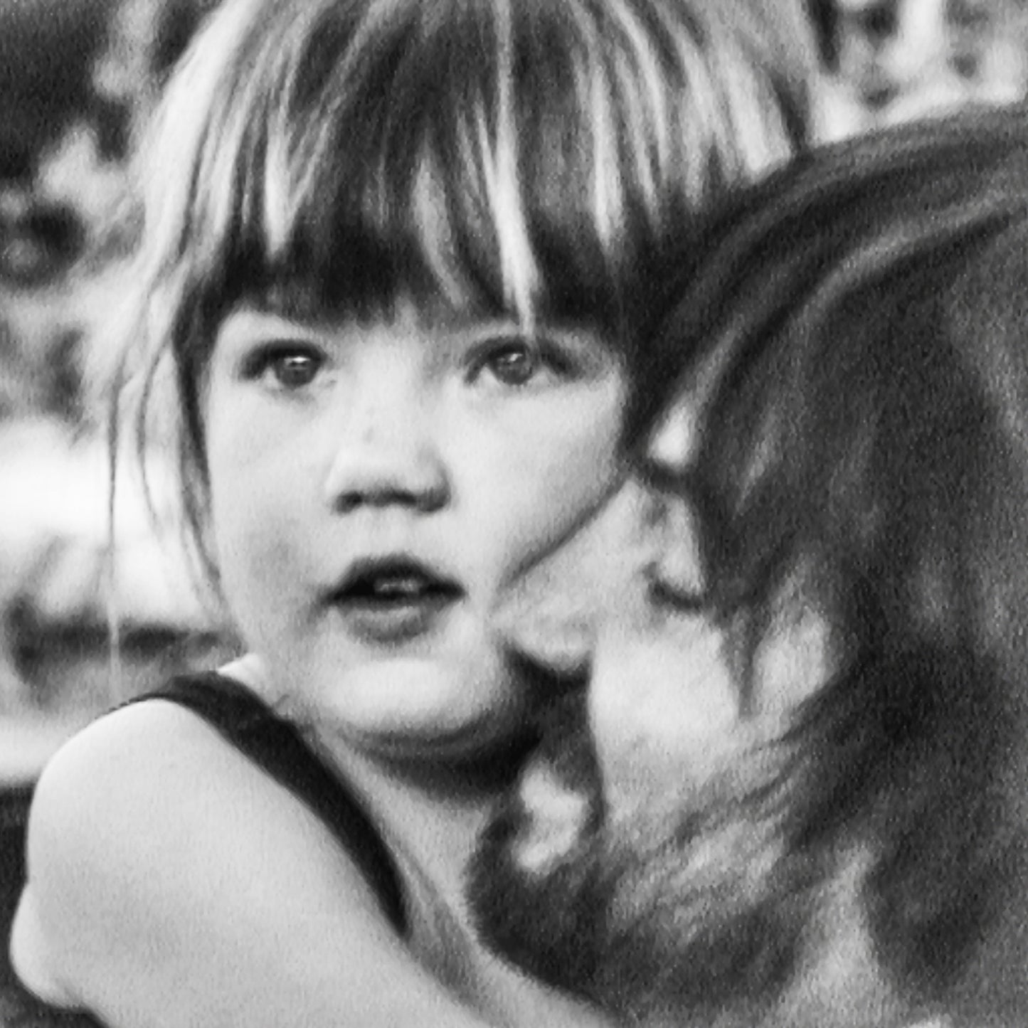 Black and white photo of a young girl with bangs and a woman's head.