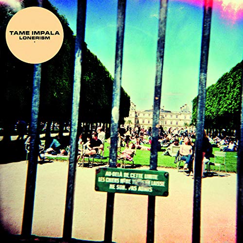 View through a metal fence of people sitting in a park with a sign.