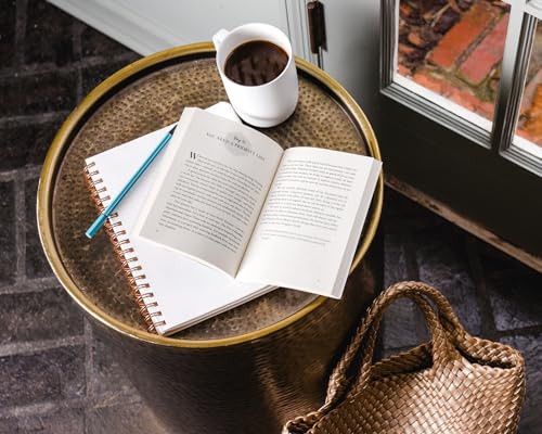 Open book, coffee cup, and notebook on a metallic side table.
