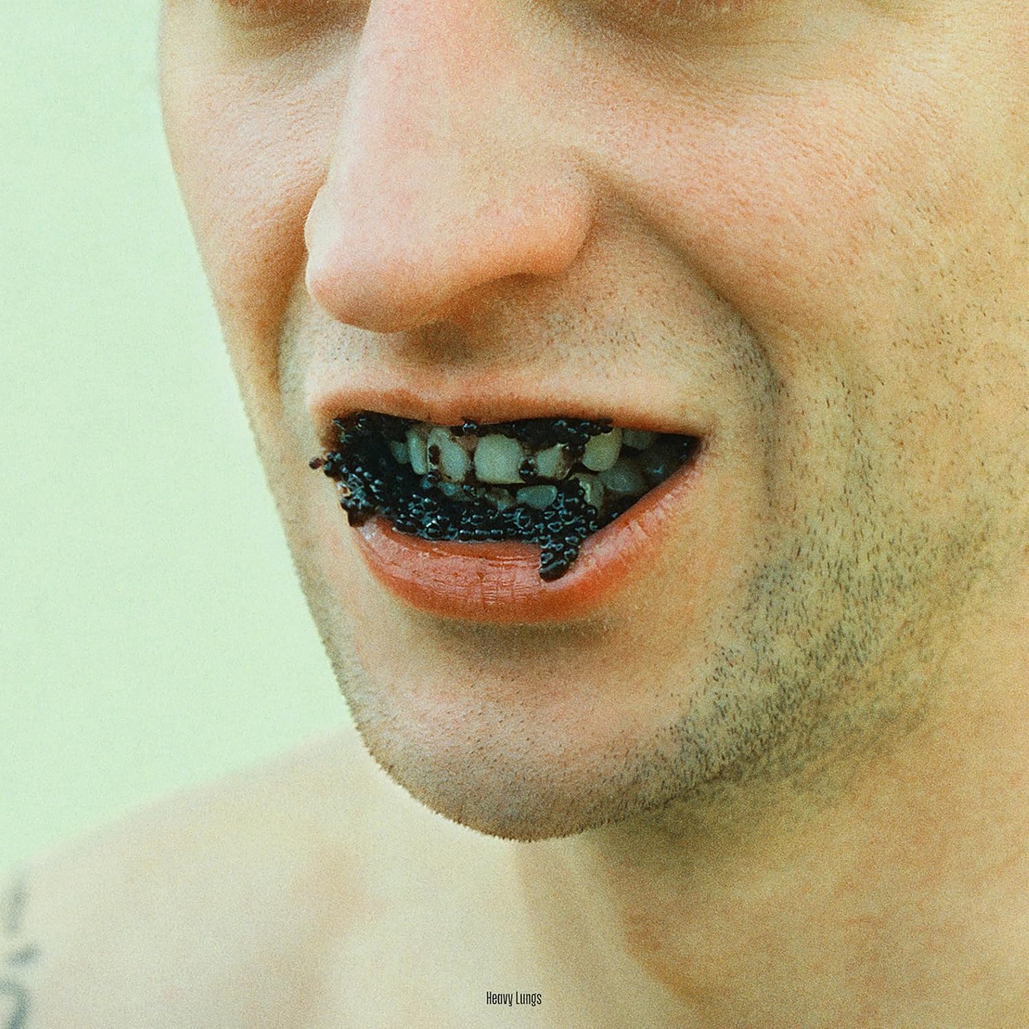 Close-up of a person's mouth with teeth covered in black caviar.