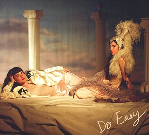 Two women in elaborate costumes pose dramatically amidst classical columns.