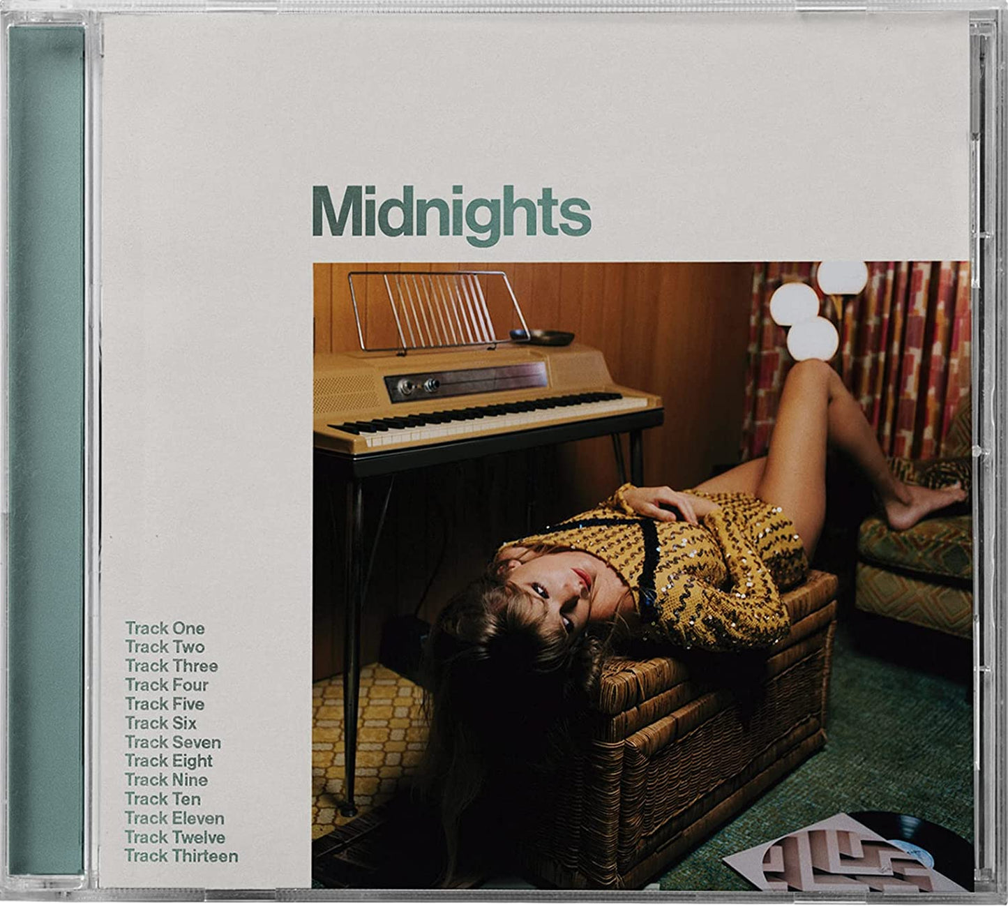 Taylor Swift's "Midnights" CD cover with a woman lounging near a piano.