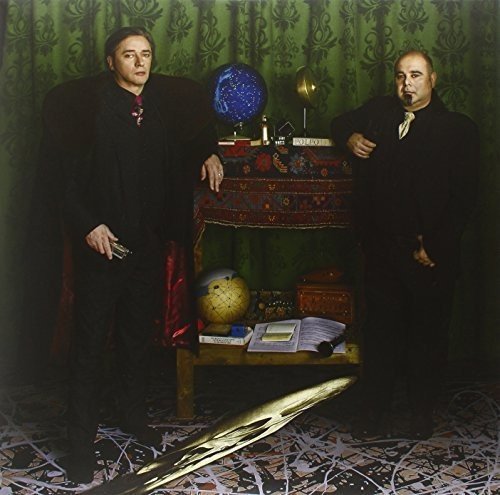 Two men in dark clothing stand beside a table with globes.