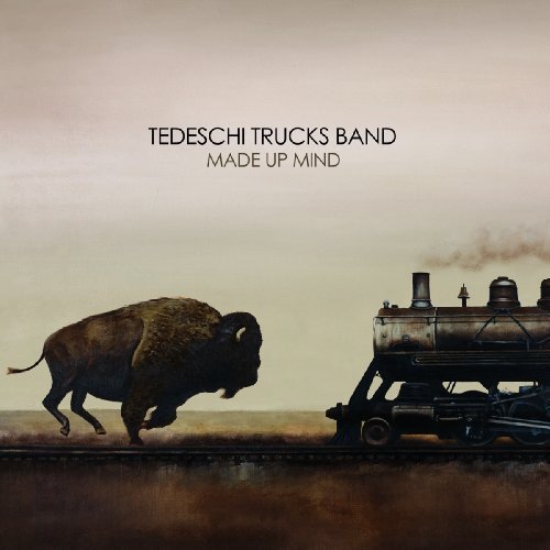 "Album cover featuring a bison running alongside a steam train on a track."