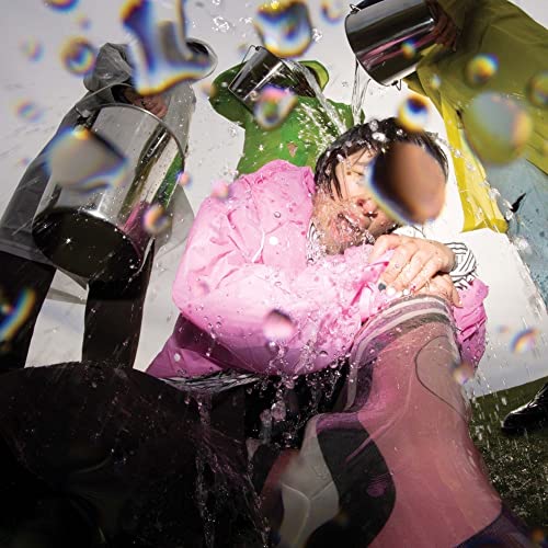 A person in a pink jacket gets splashed with water from buckets above.