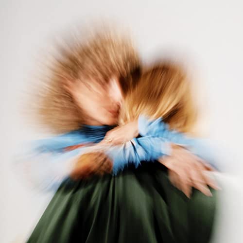 Blurred image of a person in blue and green clothing, embracing.