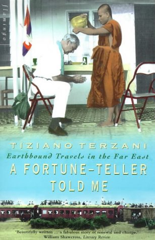 A Buddhist monk pours water over a man sitting on a chair outdoors.