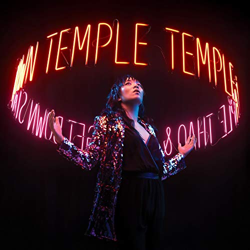 Woman in sequined jacket under a glowing neon “TEMPLE” sign.