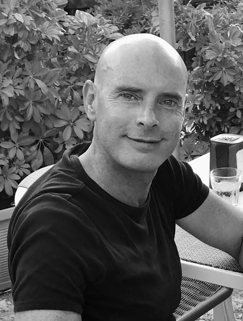 Black and white portrait of a smiling, bald man outdoors.