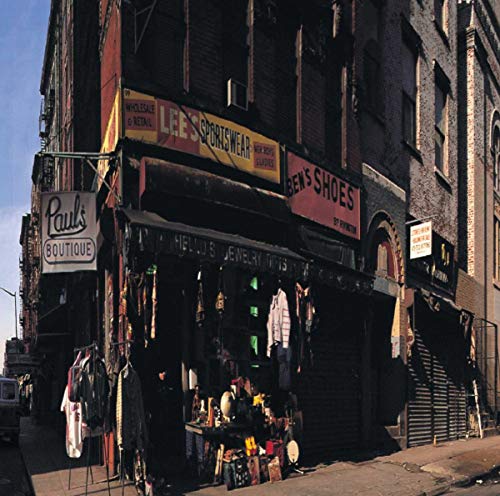 Street corner storefront with signs, clothing, and assorted merchandise displayed.