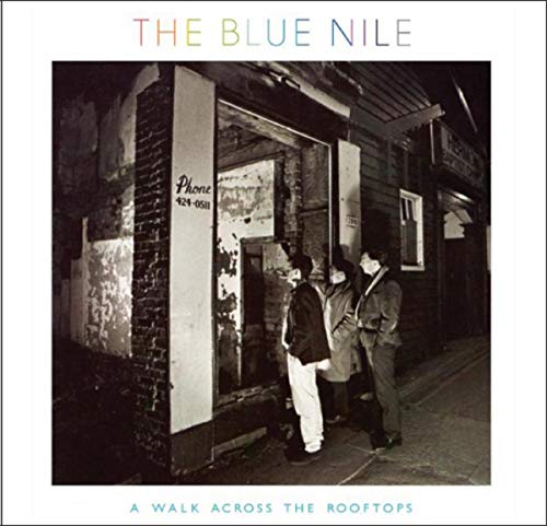 Black and white album cover showing three men standing outside a dark building doorway.