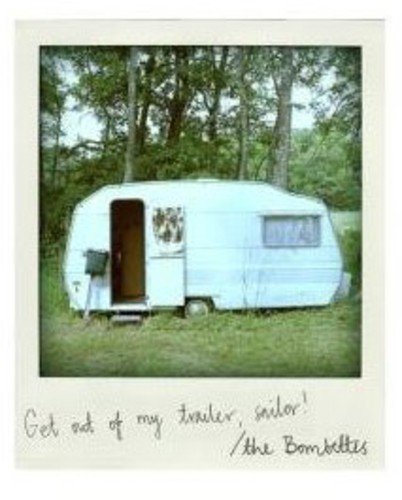 Polaroid photo of a white camper trailer in a wooded area with handwritten text.