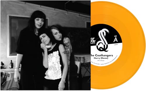 Black and white photo of The Coathangers with a yellow vinyl record.