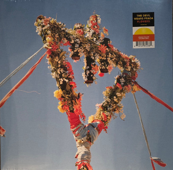 A Maypole decorated with colorful flowers and ribbons against a clear blue sky.