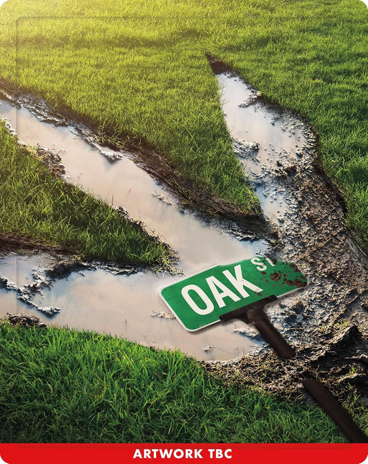 Green "Oak St" sign partially submerged in muddy, grassy ground.