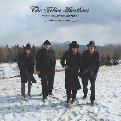 Four men in hats stand in a snowy, wintry landscape.