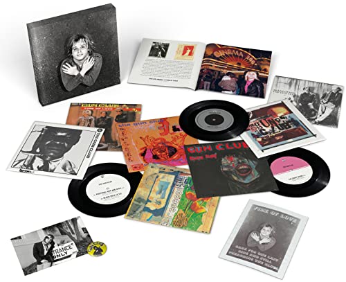 Vinyl record, booklet, and assorted black and white photographs scattered on white background.
