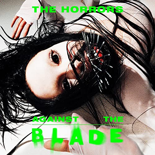 Vinyl album cover: woman with blades near face, green text.