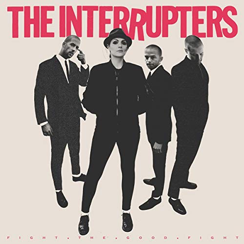 The Interrupters band members in black suits stand against a light background.