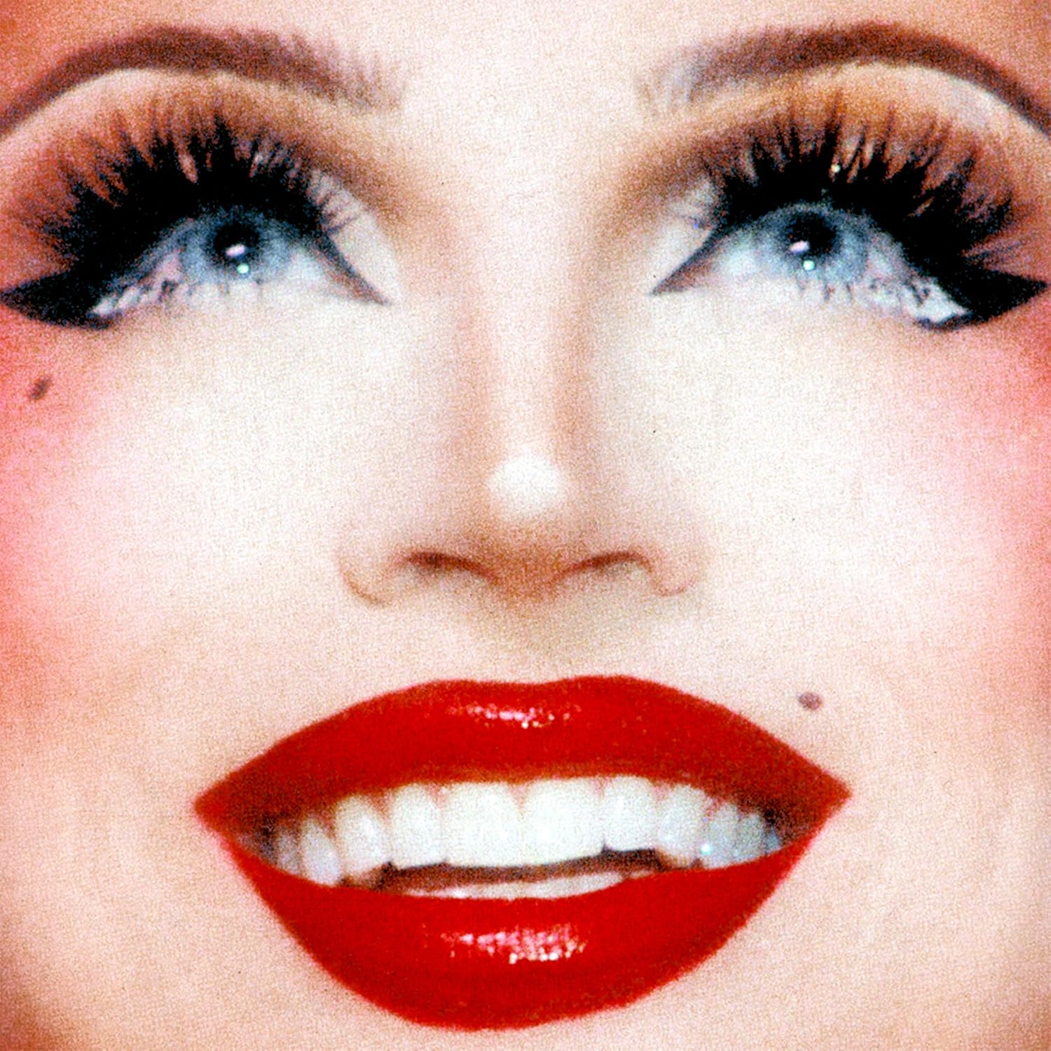 Close-up of a person with dramatic makeup, red lips, and long lashes.