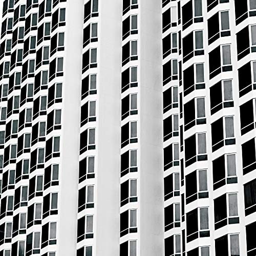 Black and white architectural pattern of repeating windows on a tall building facade.
