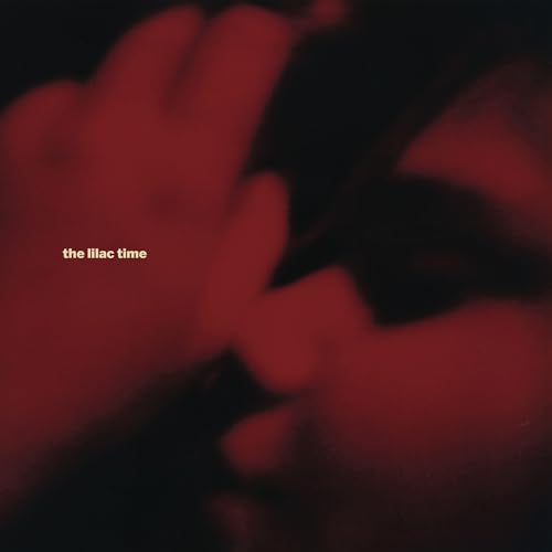 A blurry, dark red close-up of a person's face with text reading the lilac time.