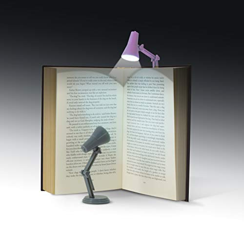 A small mint-colored book light clipped to an open book, illuminating the pages.