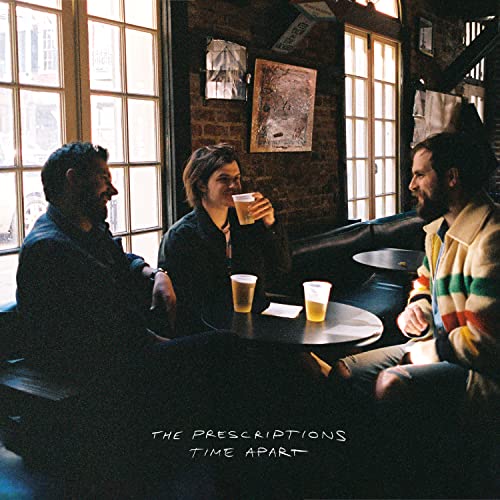 Three men sit at a table with drinks in a dimly lit bar.