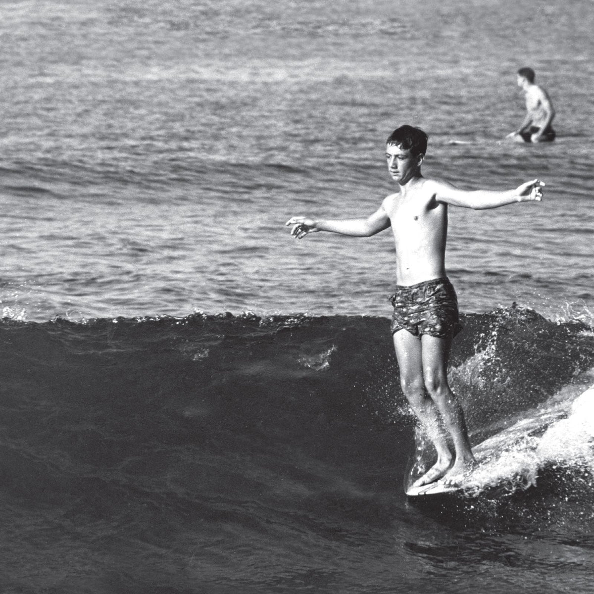 Black and white photo of a surfer riding a wave, ocean background.