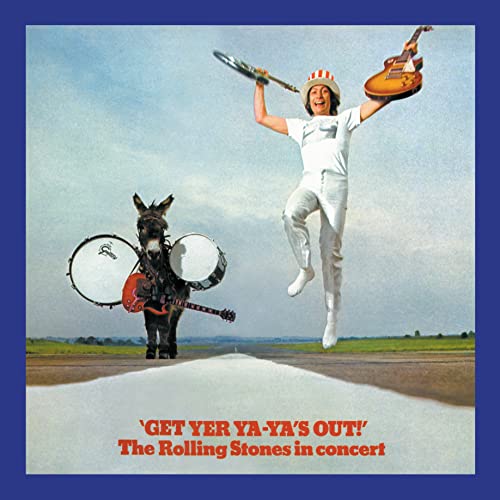 Album cover: man jumping with instruments, donkey, and drum in a field.