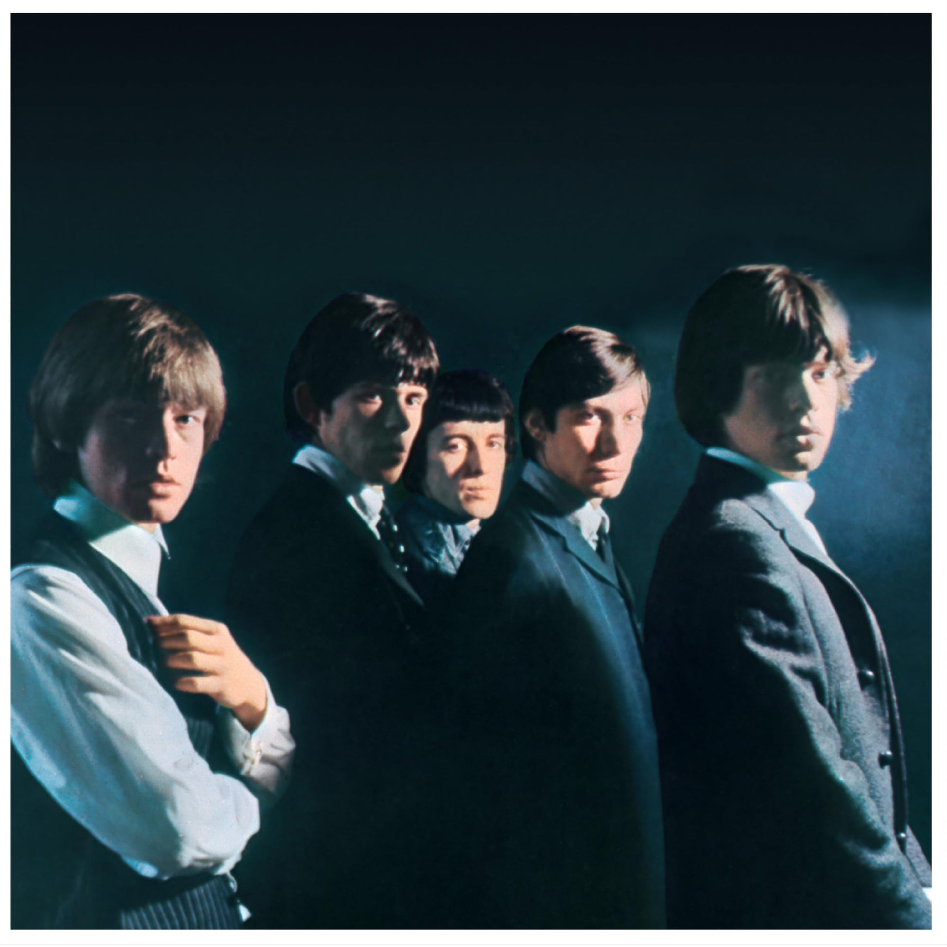 The Rolling Stones band portrait in dark suits, looking to the left.