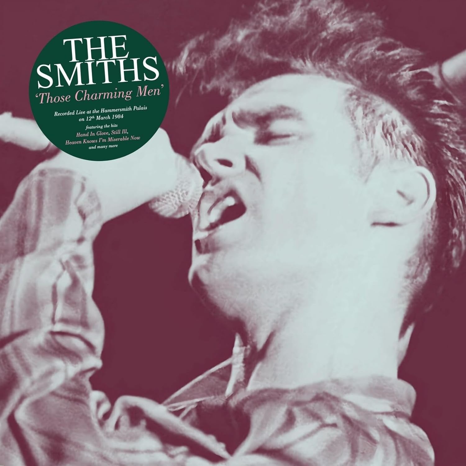 A monochrome close-up of a singer performing into a microphone with a green circular label.