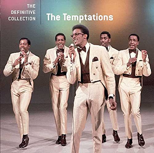 The Temptations in matching cream-colored suits performing on stage against a colorful background.