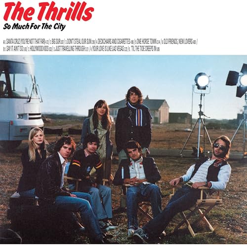 The Thrills band members sit on chairs outdoors near a tour bus and lights.