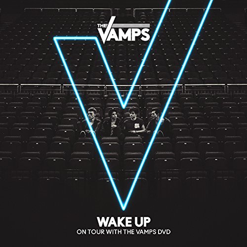 The Vamps band sitting in an empty theater with a large blue "V" overlay.