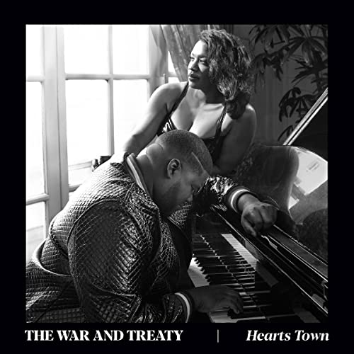 Black and white photo of a couple by a piano, album cover.