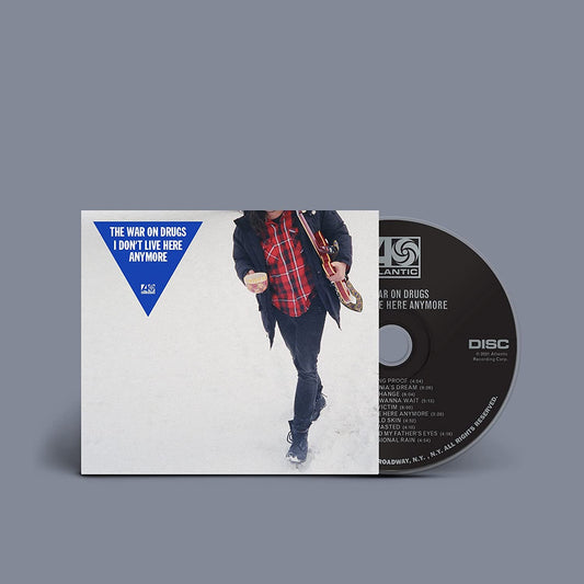 "Album cover with a person walking in snow, holding a guitar, and a blue triangle."