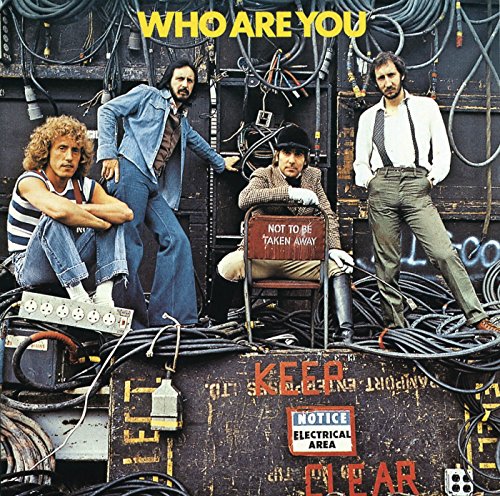 The Who band members posing amidst electrical equipment and wires.