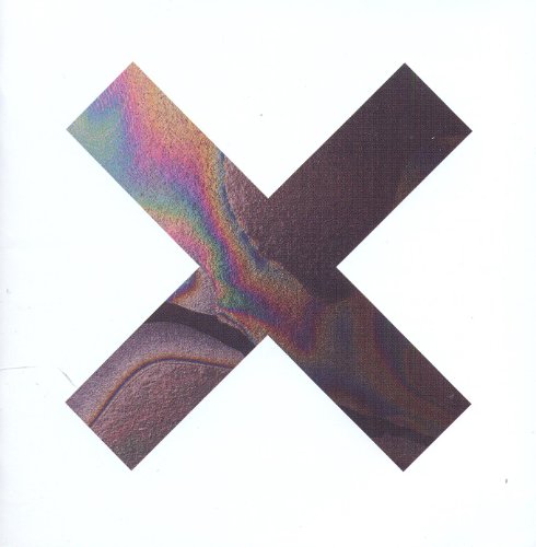 Colorful, iridescent "X" shape over a dark background, album cover art.