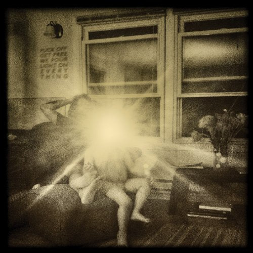 Sepia-toned image of figures near windows with bright light flare.