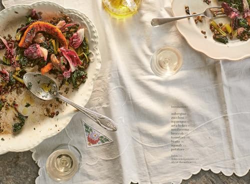 Overhead view of colorful roasted vegetables on a white tablecloth.