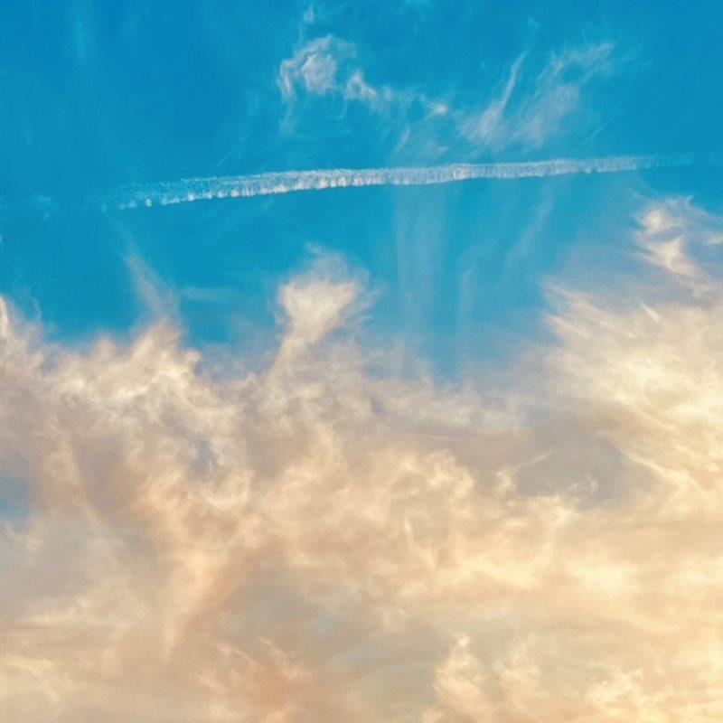 Blue sky with wispy white and peach-colored clouds.