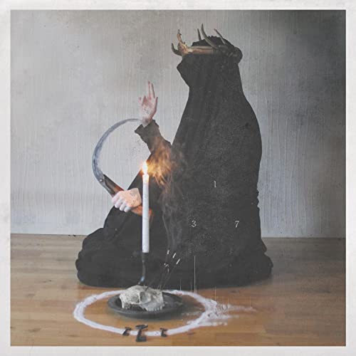Dark figure with crown, skull, candle, and ritualistic markings on a floor.