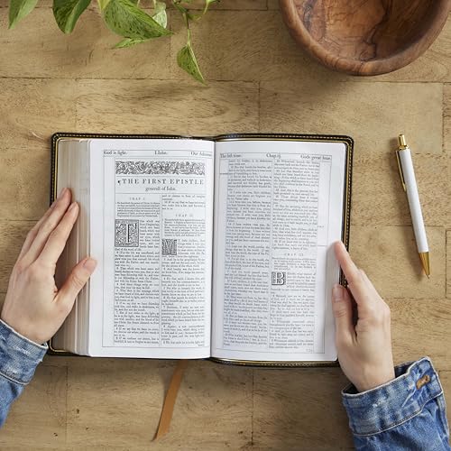 Open hardcover Bible with visible text, held by hands with a pen nearby.