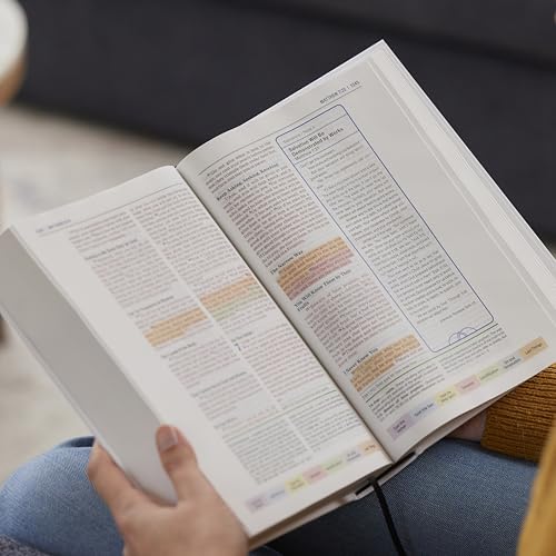 Open hardcover Bible with color-coded text, held in a person’s hands.
