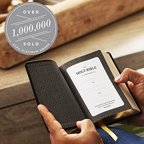 Hands holding an open KJV Holy Bible showing a presentation page with patterned endpapers.