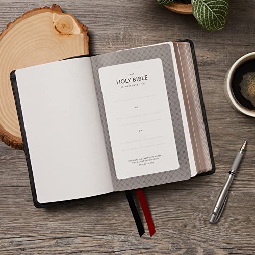 Open black Bible with presentation page, ribbon marker, and nearby coffee.