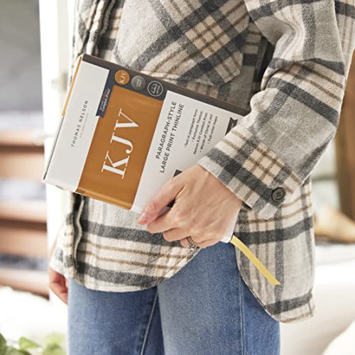 Person in a plaid shirt holding a KJV Holy Bible in its packaging.