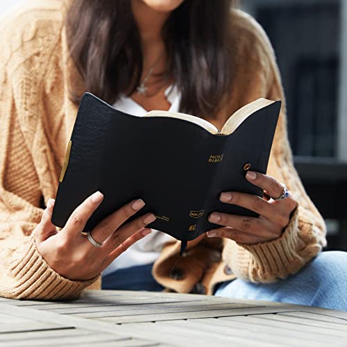 Black leather checkbook-style Bible open in a person’s hands.