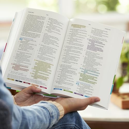 Open pink Bible with color-coded text held in a person’s hands.